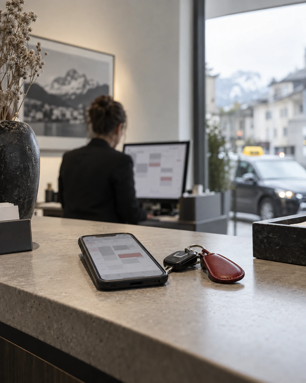 Empfangstheke mit Terminkalender auf dem Handy, Autoschlüssel daneben