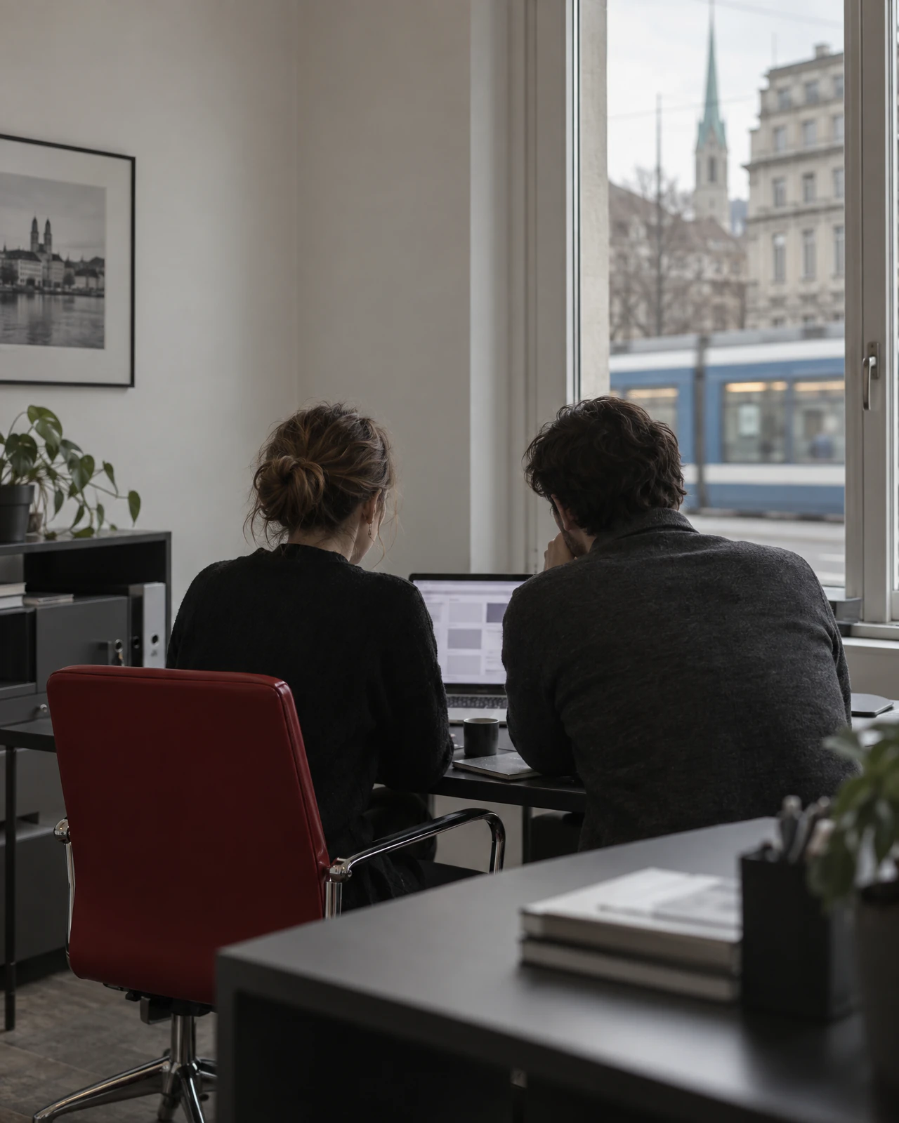 Zwei Personen prüfen in einem Büro in Zürich eingehende Anfragen auf einem Laptop