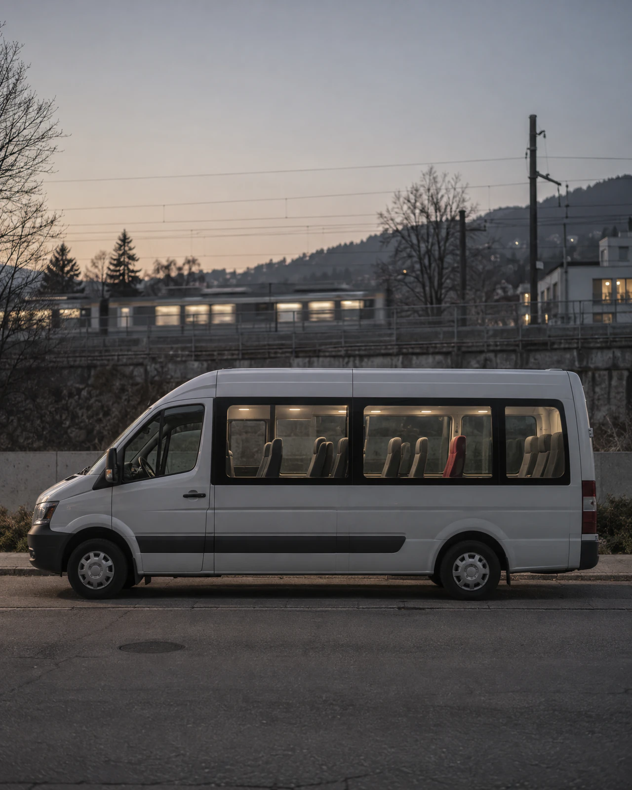 Kleinbus mit beleuchtetem Innenraum und leeren Sitzen am Abend an einem ruhigen Strassenrand